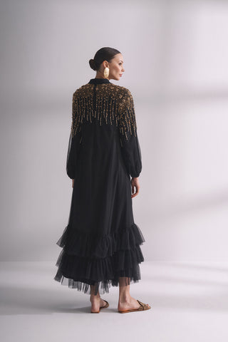 Платье с ниспадающим вырезом, украшенное камнями и плиссированными рукавами.